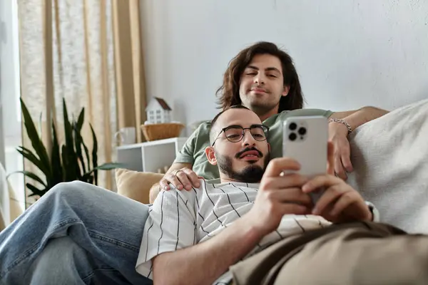 Gay casal aconchegante juntos: um no telefone, outro cochilando no ombro do parceiro — Fotografia de Stock