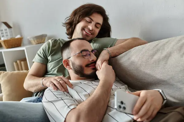 A couple cuddles on a couch, one man gazing lovingly at his partner. — Stock Photo