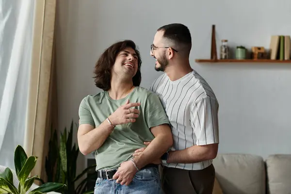 Two men embrace and laugh together in their living room. — Stock Photo