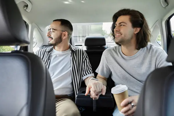 A gay couple, holding hands, rides in the back seat of a car. — стоковое фото