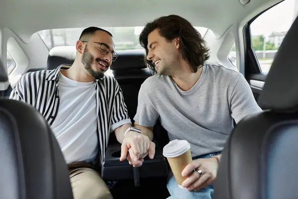Deux hommes rient ensemble en se tenant la main sur le siège arrière d'une voiture. — Photo de stock