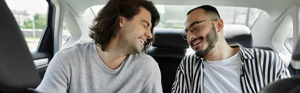 Two men laugh together in the backseat of a car. — Stock Photo