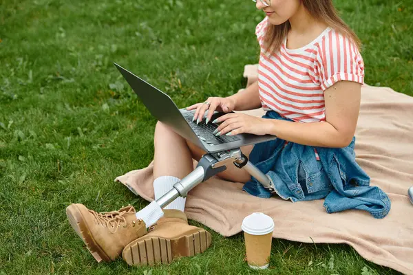 Uma jovem mulher em uma roupa de verão trabalha em seu laptop enquanto se senta em um cobertor em um parque. — Fotografia de Stock