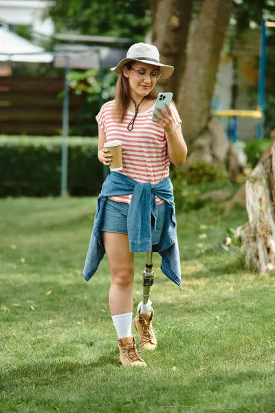 Eine junge Frau mit Beinprothese geht durch einen Park und genießt einen sonnigen Sommertag. — Stockfoto