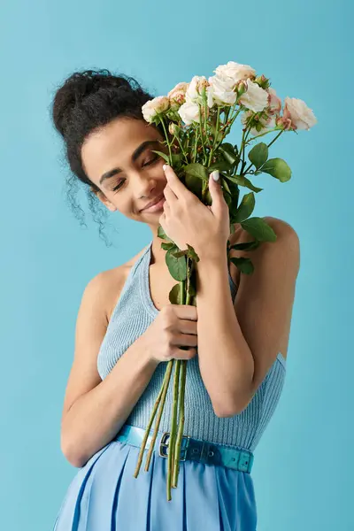 Una giovane donna in abito blu, sorride dolcemente mentre tiene vicino al viso un mazzo di rose bianche. — Foto stock