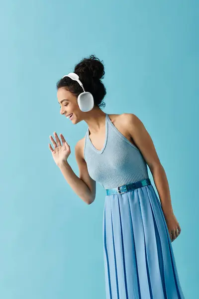 Una giovane donna in abito blu balla e canta con la musica nelle cuffie. — Foto stock