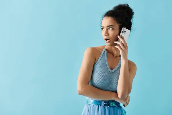 Une jeune femme en robe bleue semble surprise en parlant sur son téléphone. — Photo de stock