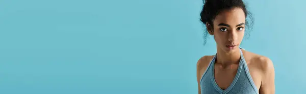 A young African American woman in a blue halter top stares directly at the camera with a confident expression. — Stock Photo
