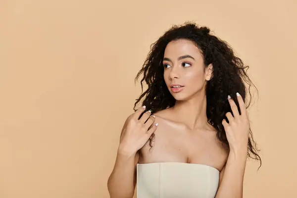 A young woman with curly hair and bare shoulders, gazing off to the side, exudes confidence and natural beauty. — Stock Photo