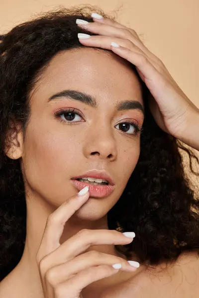 Una giovane donna con i capelli ricci guarda nella macchina fotografica, la mano delicatamente toccando le labbra. — Foto stock