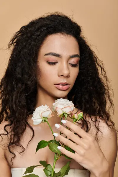 Uma jovem mulher com cabelo escuro e encaracolado segura rosas brancas, sua expressão suave e contemplativa. — Stock Photo