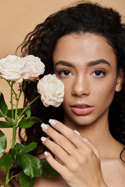 Una giovane donna con la bellezza naturale e le spalle nude tiene una rosa bianca vicino al suo viso, i suoi occhi che guardano dolcemente. — Foto stock