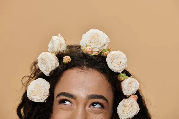 A young African American woman with natural makeup and flowers adorning her hair looks up thoughtfully. — Stock Photo