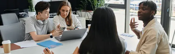 Quatro indivíduos colaboram em torno de uma mesa, envolvidos em uma discussão animada. — Fotografia de Stock