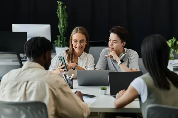 A diverse team of young professionals collaborates on a project, focused on a smartphone. — Stock Photo