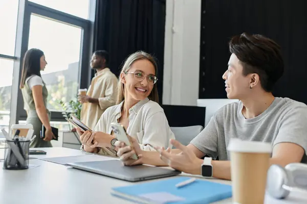 Two colleagues work together at a desk in a modern office space. — Stock Photo