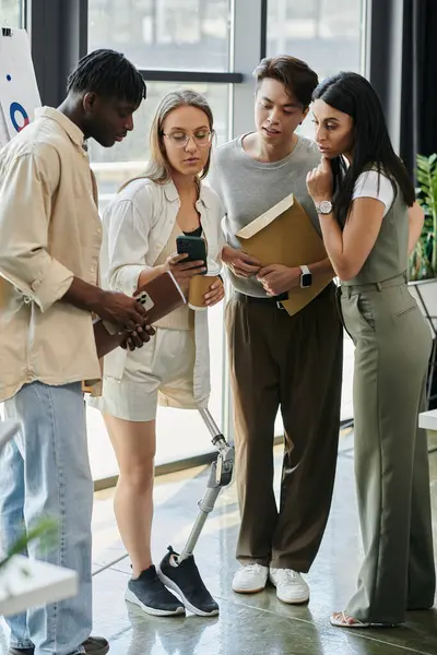 Four colleagues gather around a smartphone, discussing ideas for a new business venture. — Stock Photo