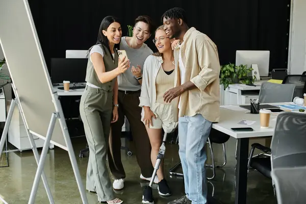 Quatre collègues se réunissent dans un bureau, souriant et prenant une photo avec un smartphone. — Photo de stock