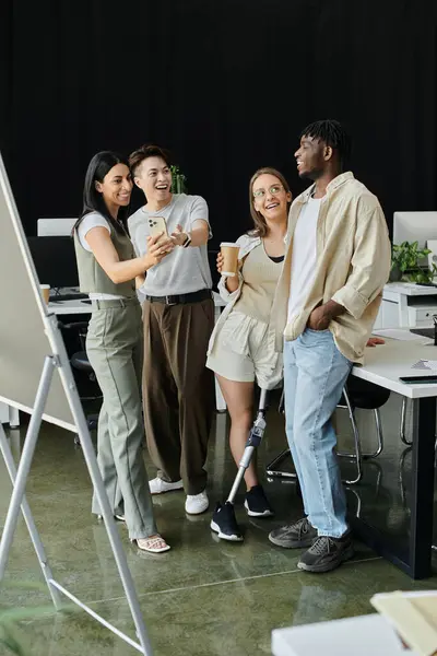 Cuatro colegas hacen una pausa en su trabajo para tomarse una selfie en un espacio de trabajo contemporáneo. - foto de stock