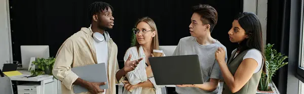 Four colleagues collaborating on a project using laptops and discussing ideas. — Stock Photo