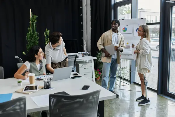 Four colleagues collaborate in a modern office setting, working on a startup project. — Stock Photo