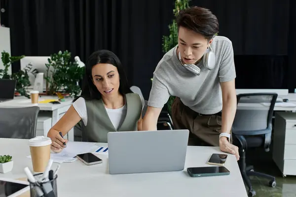Two colleagues collaborate on a laptop and paperwork at a desk in a modern office. — Stock Photo