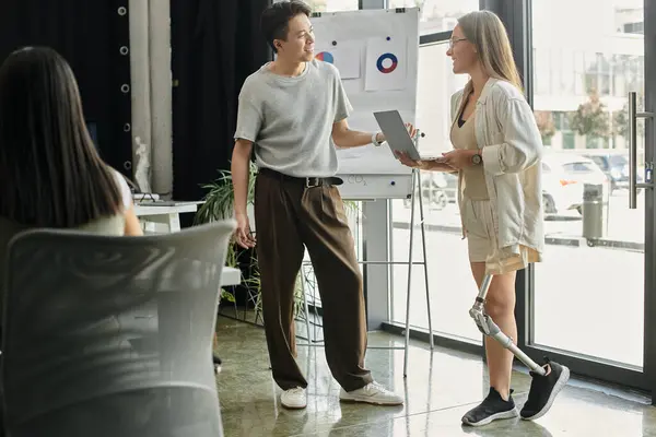 Two colleagues discuss a project while standing in an office. — Stock Photo