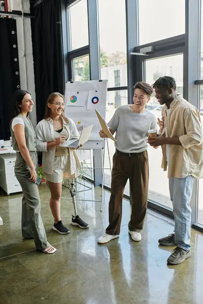Four colleagues brainstorm around a whiteboard, reviewing plans and data. — Stock Photo