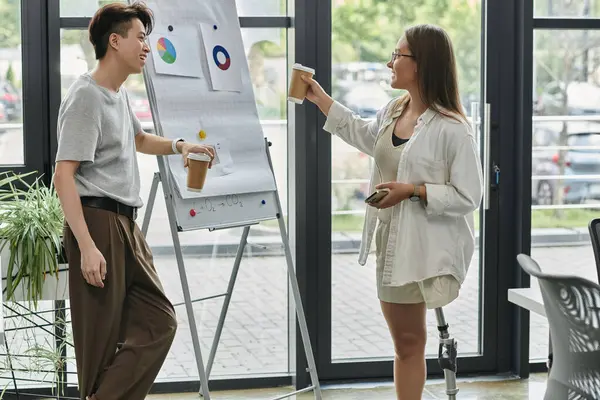 Two colleagues stand near a whiteboard, enjoying a coffee break. — Stock Photo
