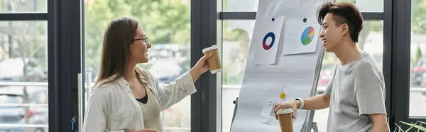 Two colleagues discussing ideas by a whiteboard with charts. — Stock Photo