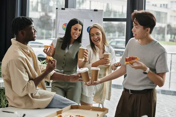 Quattro colleghi condividono pizza e caffè durante una pausa pranzo in ufficio. — Foto stock