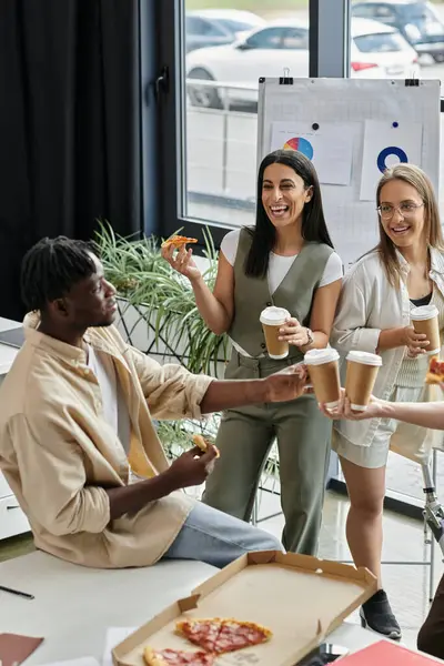 A team of young professionals enjoys a pizza break in their office. — Stock Photo