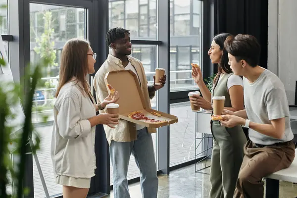 Un gruppo di colleghi si gode una pausa pizza in un ufficio moderno. — Foto stock