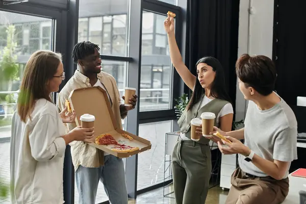 Four coworkers enjoy a pizza break during their work day, laughing and sharing slices. — Stock Photo