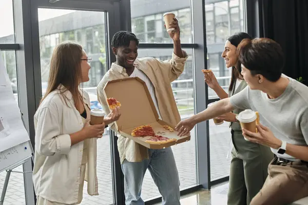 Une équipe de collègues apprécie la pizza et le café pendant une pause dans leur journée de travail occupée. — Photo de stock