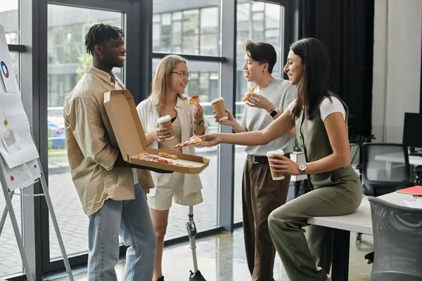 Four colleagues take a break from work to enjoy pizza and coffee in a modern office. — Stock Photo