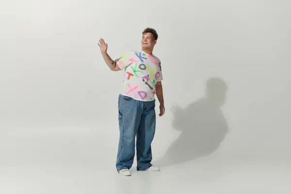 A stylishly dressed queer person with a playful expression waves in a white studio. — Stock Photo