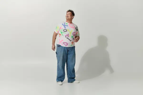 Uma pessoa queer em uma camisa branca coberta de letras coloridas olha para cima. — Fotografia de Stock