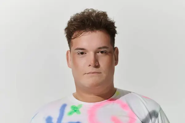 Jovens de cabelos castanhos olham para a câmera em uma camisa colorida — Fotografia de Stock