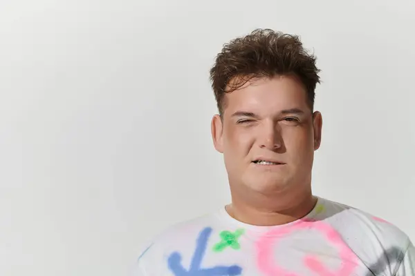 A young queer person, wearing stylish clothing with colorful accents, stares directly at the camera. — Stock Photo