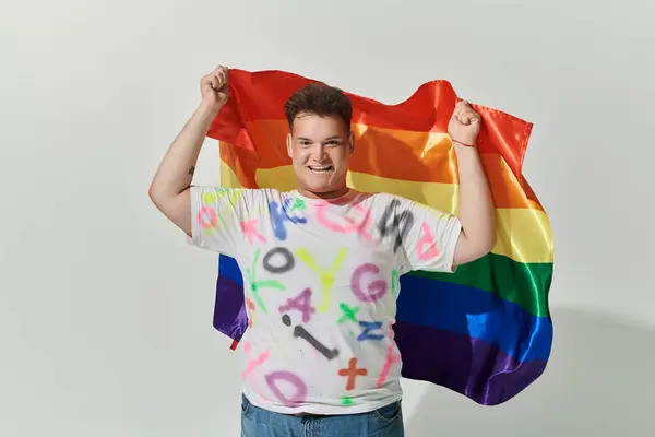Una persona alegre queer orgullosamente sostiene una bandera del arco iris. — Stock Photo