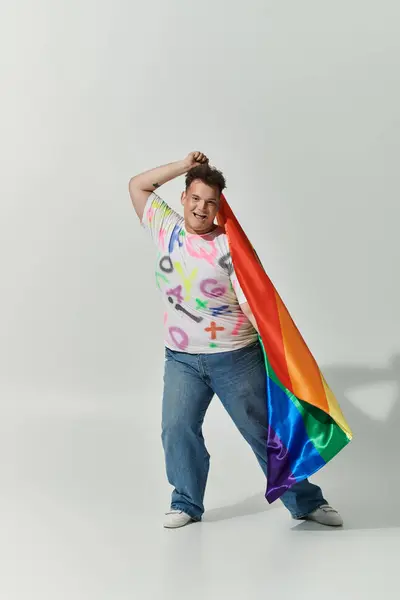 Una persona queer sorridente tiene una bandiera arcobaleno, irradiando gioia e fiducia. — Foto stock