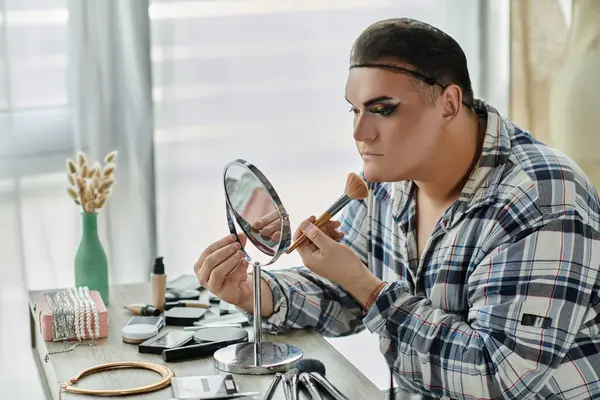 A queer person applies makeup in front of a mirror. — Stock Photo
