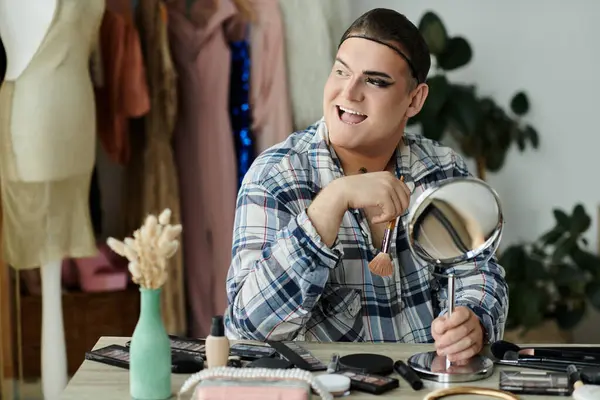 A queer person applies makeup while smiling at their reflection. — Stock Photo