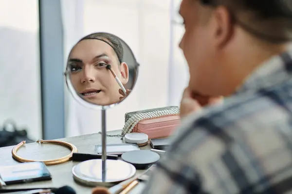 Une personne queer applique le maquillage dans un miroir. — Photo de stock