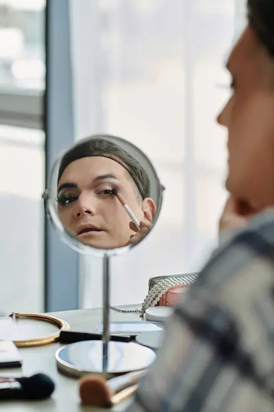 Una persona queer applica il trucco mentre guarda in uno specchio. — Foto stock