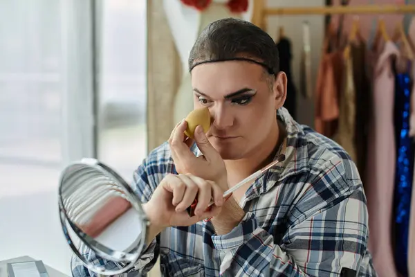 Eine queere Person schminkt sich vor einem Spiegel und konzentriert sich dabei auf ihr AugenMake-up. — Stockfoto