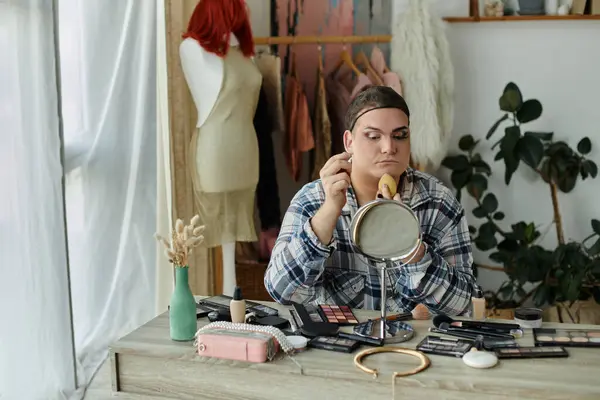 Queer personne applique maquillage dans miroir, entouré de produits de beauté et toile de fond à la mode — Stock Photo