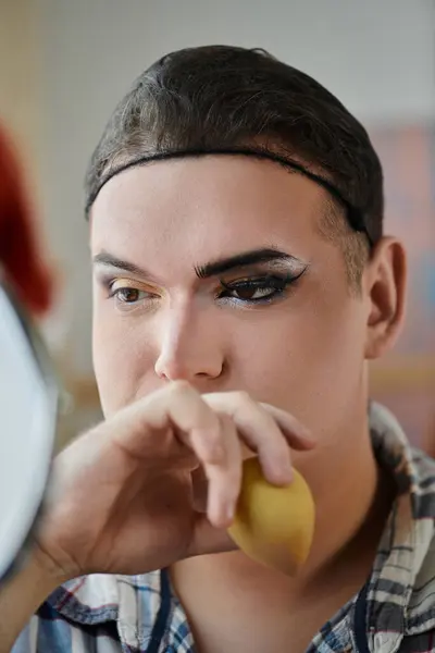 Una giovane persona queer applica il trucco, concentrandosi intensamente sul loro riflesso. — Foto stock