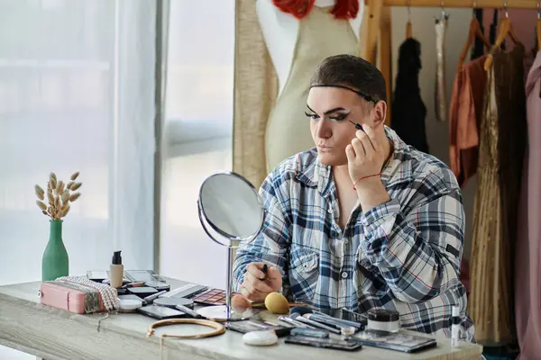 Une personne queer appliquant un eye-liner devant un miroir. — Photo de stock